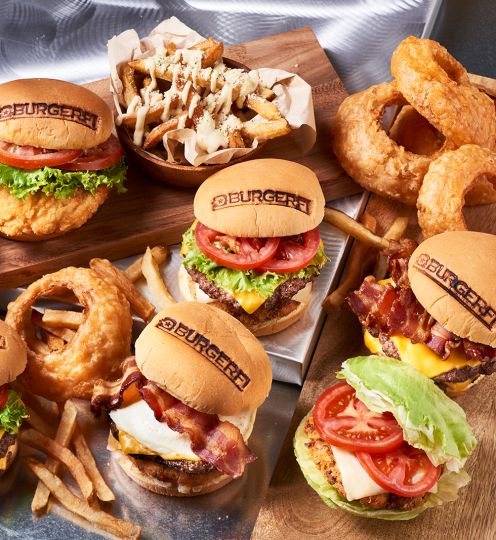 multiple burgers and sides on wooden and metal background