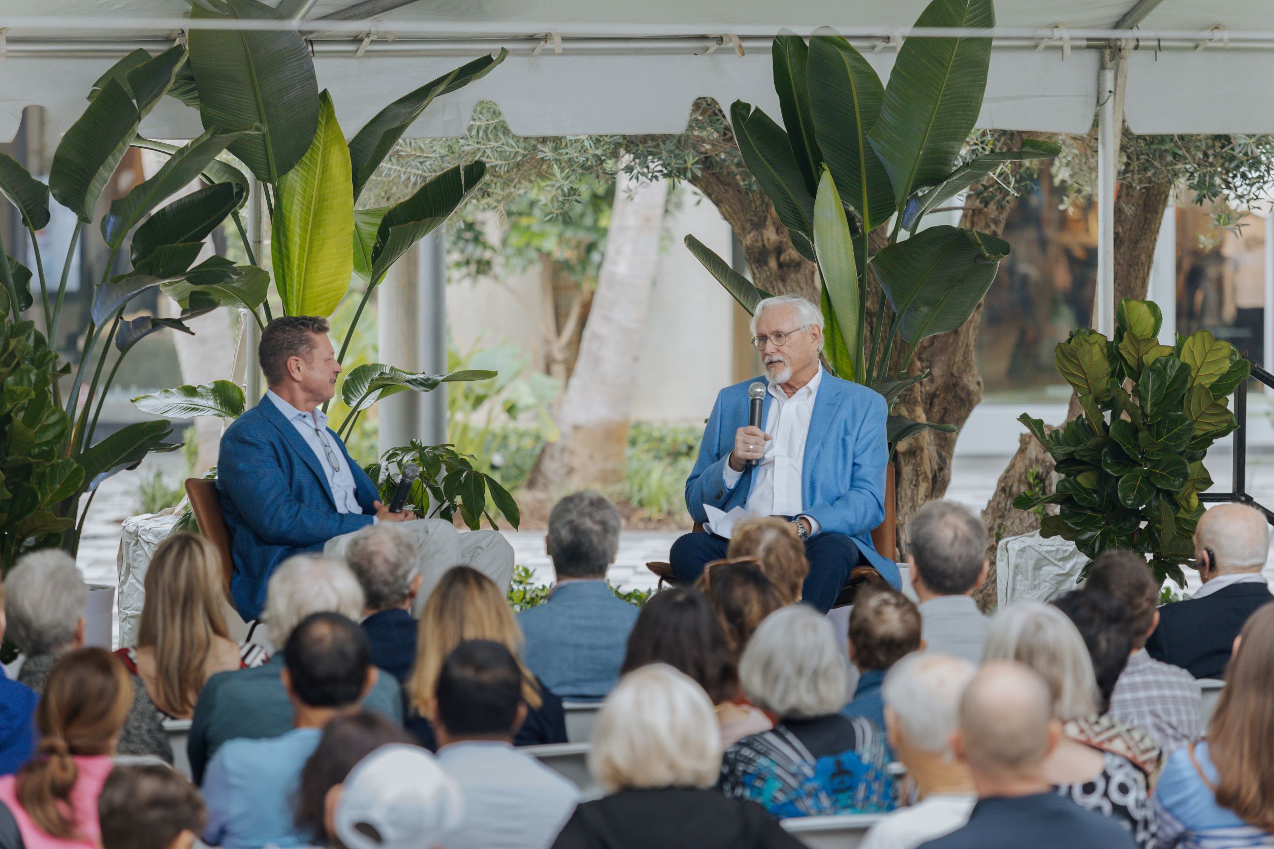 John Blades and Harvey Oyer host a discussion on a stage in front of audience 