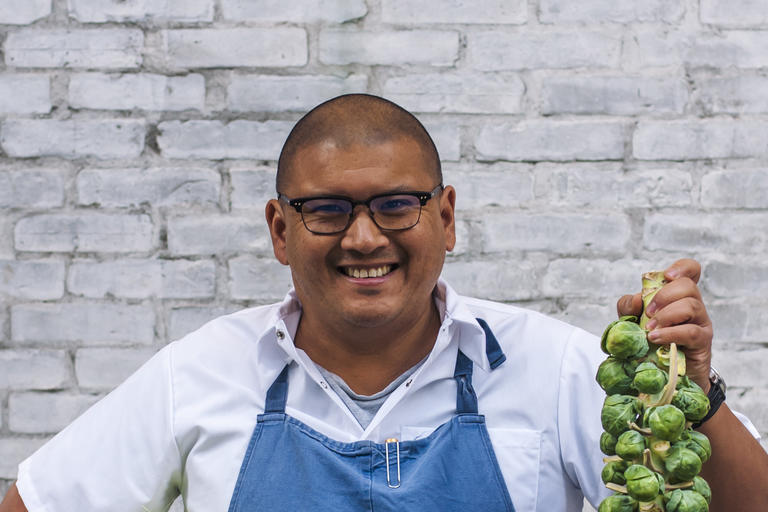 Chef holding up fresh produce while smiling
